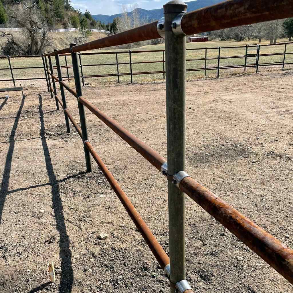 3 rail pipe fence built using pipe for post and rail and Bullet Fence Systems for the no-weld rail pipe connectors. 